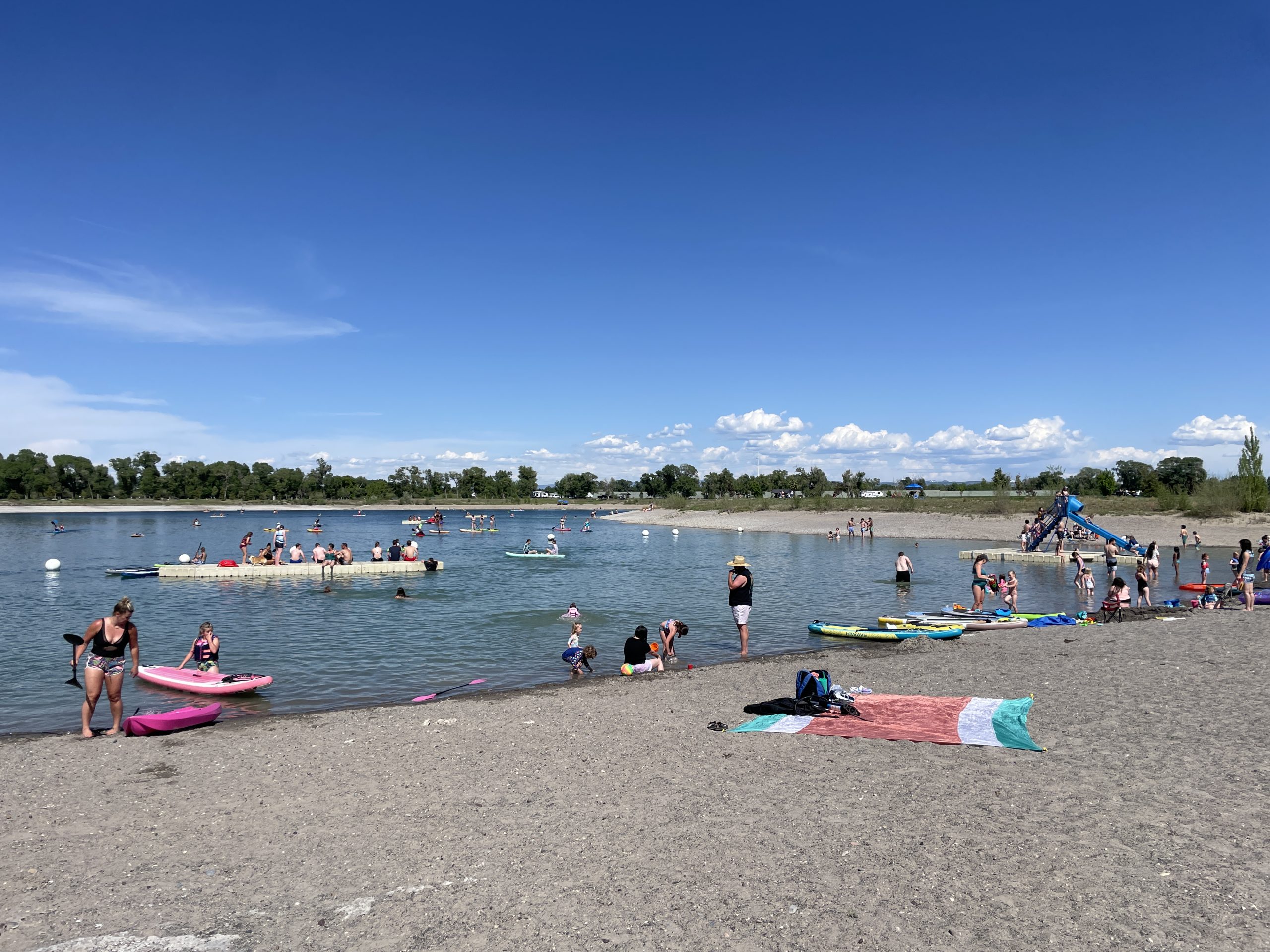 People Playing at Rigby Lake or Jefferson County Lake, in Rigby Idaho. Showing Doc and Floating Slide, and lying on the beach.