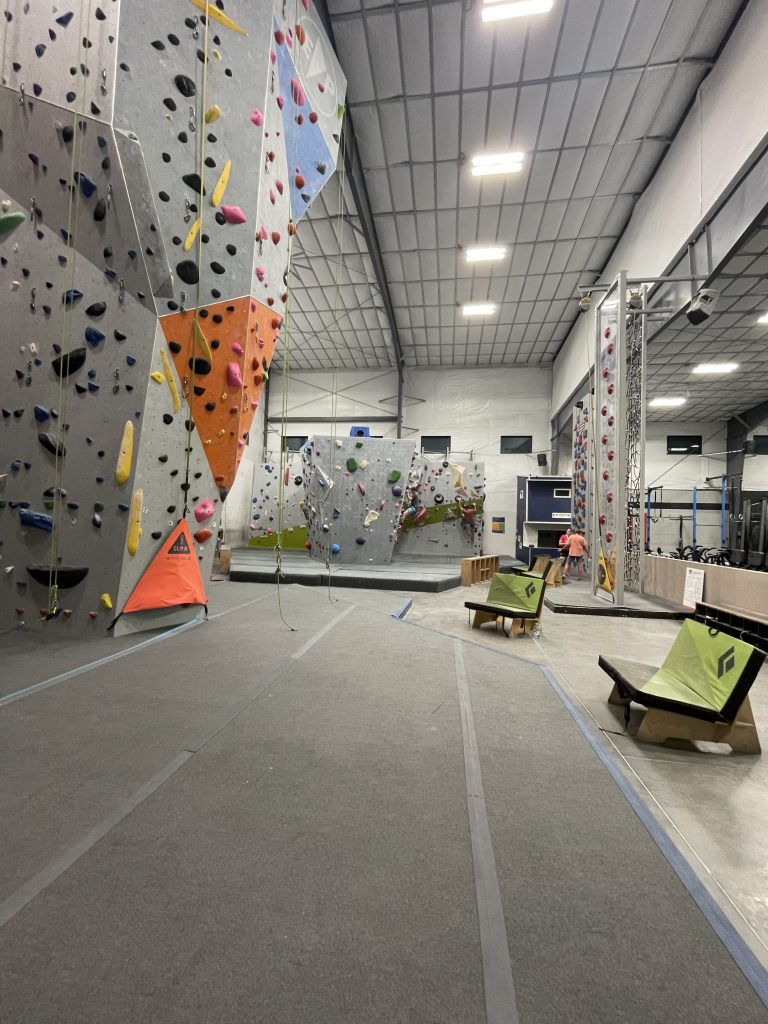 Side view of the rock climbing gym showing top rope and seats to sit down.