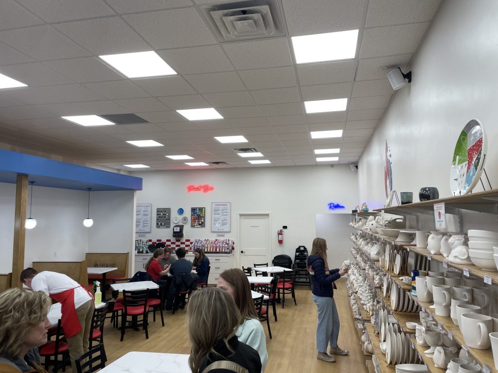 Pottery on the right and people at tables painting pottery in Fire and Rizz.