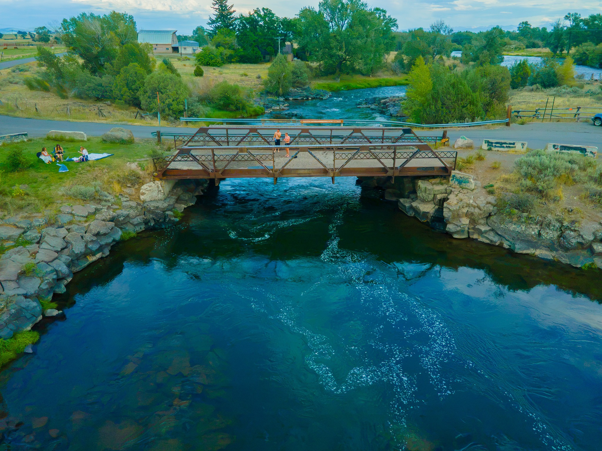 People relaxing on the grassy riverbank at Twin Bridges near Rexburg, Idaho
